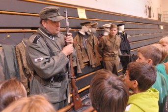 Ed Patterson (top left), Valley Falls, and Dylan Callahan, Emporia, provided a display of World War II uniforms and weapons for students to view during History Day at Valley Falls schools.